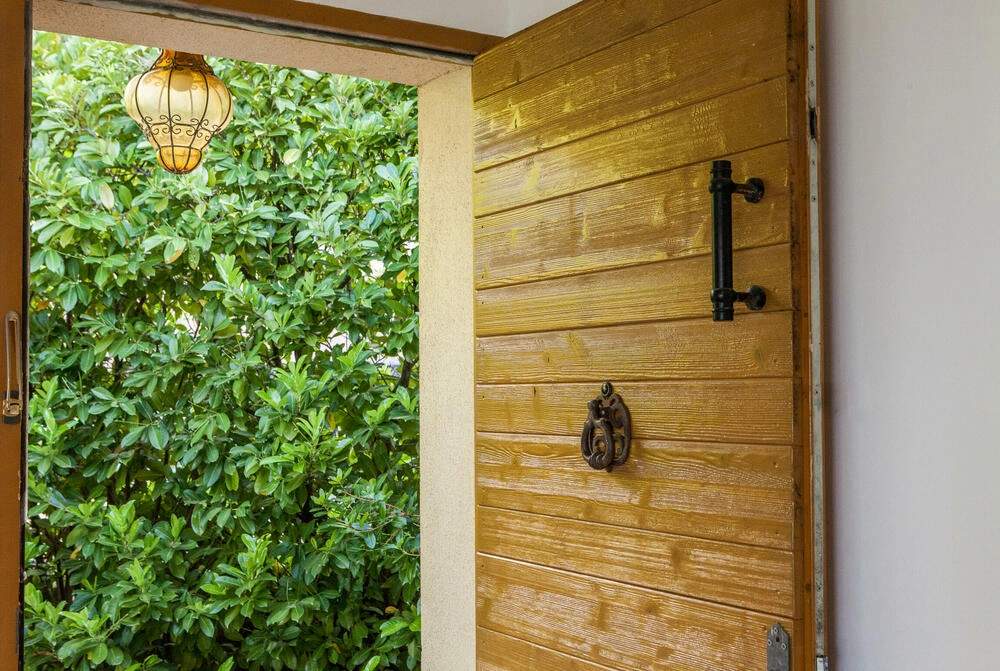 Entrée élégante d'une résidence de luxe avec porte en bois et jardin verdoyant