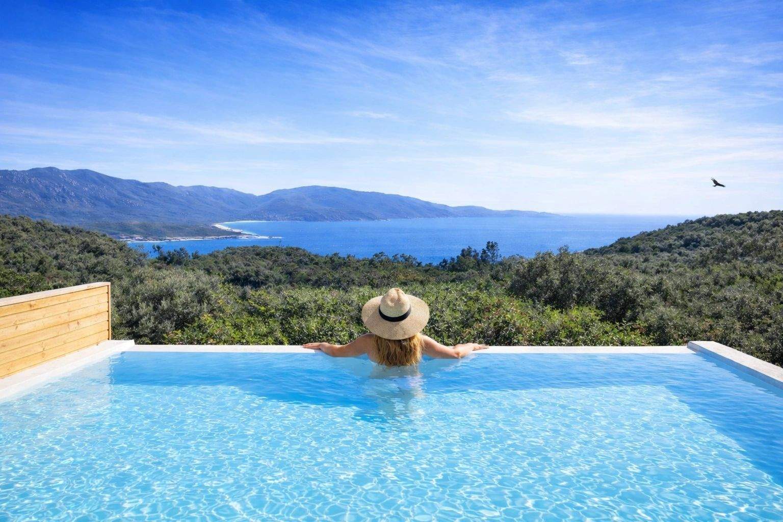 Femme dans piscine à débordement face à la mer bleue, villas de luxe avec vue côtière