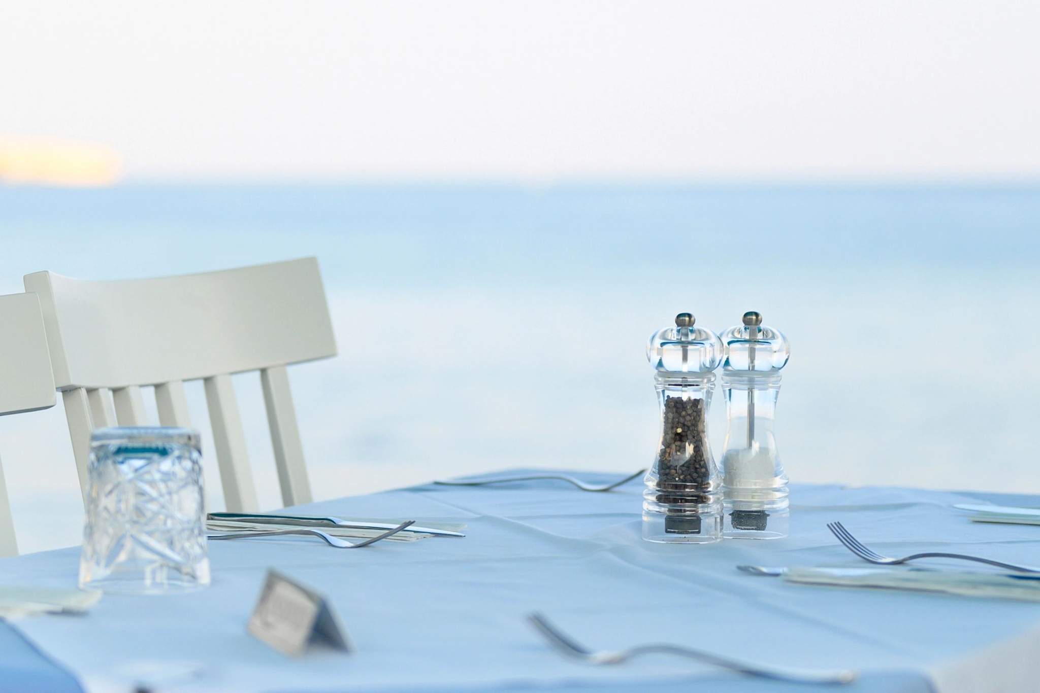 Table de restaurant en bord de mer avec vue sur piscine et villa