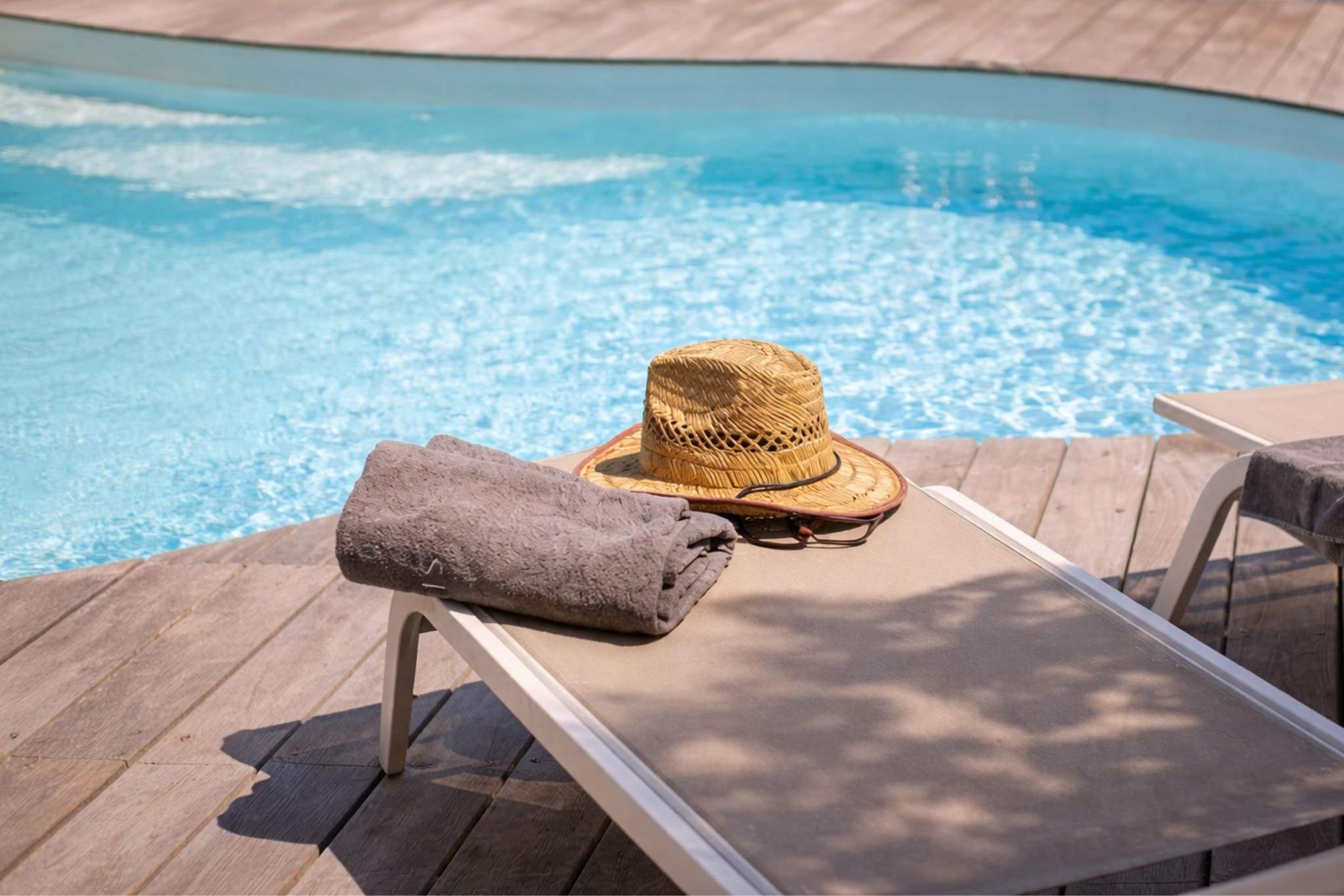 Villa avec piscine, chaise longue, serviette et chapeau de paille au bord de l'eau
