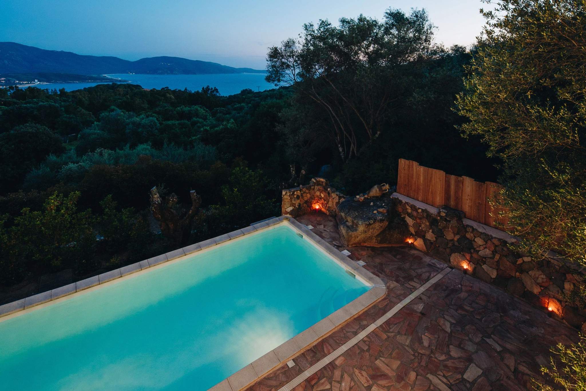 Résidence de luxe avec piscine turquoise surplombant la mer Méditerranée au coucher du soleil