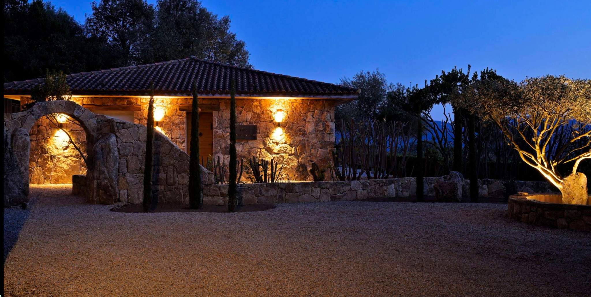 Résidence de luxe illuminée la nuit avec architecture en pierre et jardin paysager